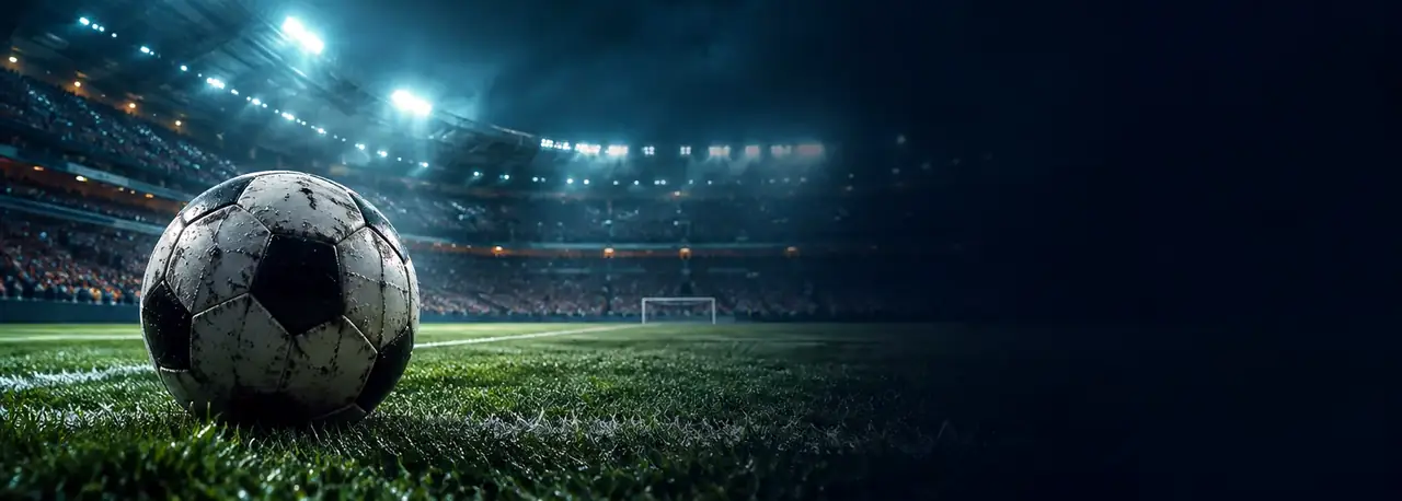 Ballon de football sur la pelouse d'un stade illuminé, un soir de match